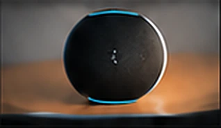 A small dark spherical speaker resting on a warm-lit surface.