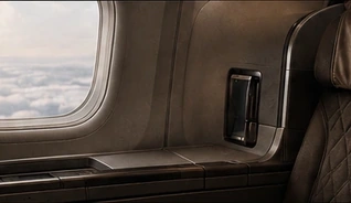 The window and quilted seatback of a premium airline cabin, cloud tops visible outside.
